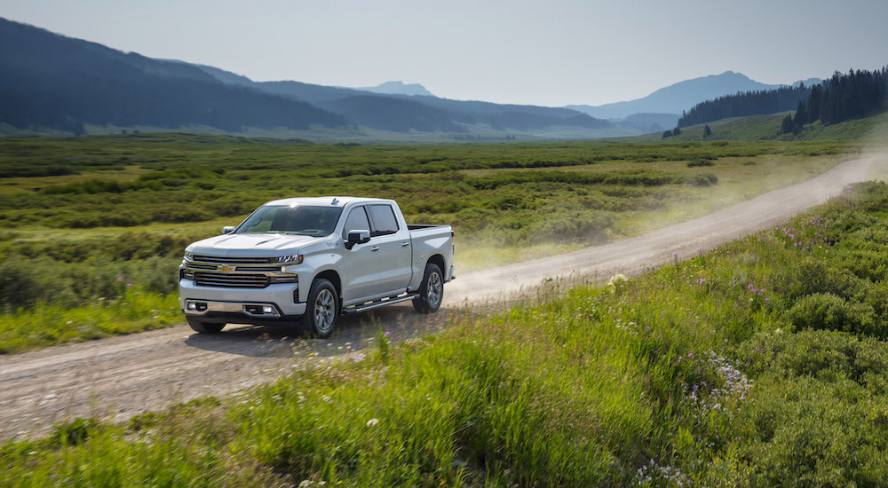 The brand new 2019 Chevy Silverado 1500 is driving down a dirt road with the mountains in the background. 