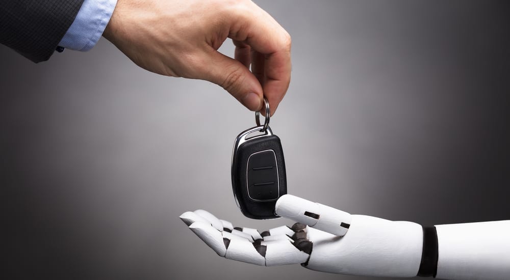 A human hand is shown handing off car keys to a robotic hand.
