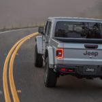 A silver 2022 Jeep Gladiator is shown from the rear driving on a foggy road.