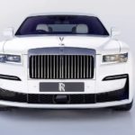 A white Rolls Royce Ghost is shown from the front on a light grey background.