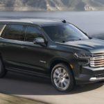 A black 2022 Chevy Tahoe High Country is shown from the side driving on an open road.