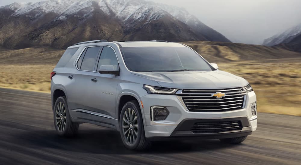 A silver 2022 Chevy Traverse is shown from the front driving on an open road.
