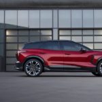 A red 2024 Chevy Blazer EV is shown from the side while parked in front of garage doors.