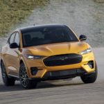 A yellow 2023 Mustang Mach E GT is shown from the front while sliding.