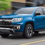 A blue 2022 Chevy Colorado Z71 is shown driving on a city street after leaving a Chevy truck dealership.