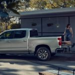 A couple is shown loading the bed of a silver 2023 Chevy Silverado 1500 Z71 in a driveway.