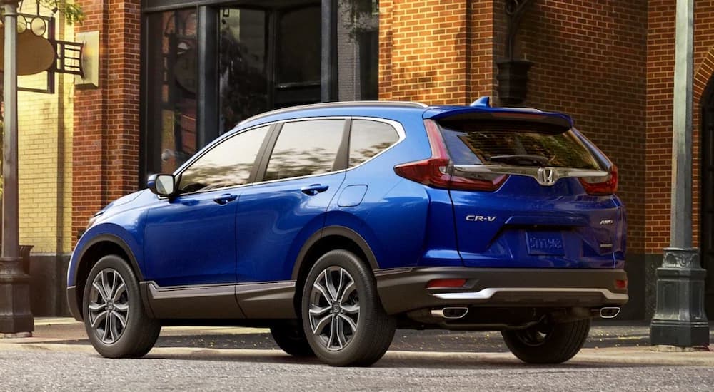 A blue 2019 Honda CR-V is shown parked next to a brick building.