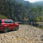 A red 2023 Nissan Armada for sale seen parked off road by a stream.