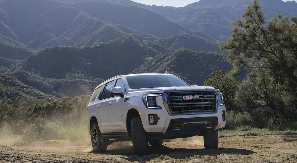 A white 2022 GMC Yukon AT4 is shown from the front at an angle.