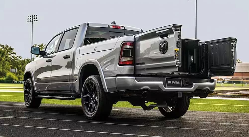 The rear side angle and truck bed hatch is shown on a silver 2023 Ram 1500.