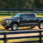 A black 2021 Ford F-150 is shown driving on a dirt road.