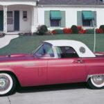 A red and white 1957 Ford Thunderbird is shown parked on a neighborhood street.