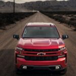 A new Chevy Silverado for sale, a red 2023 Chevy Silverado 1500 RST, is shown driving.