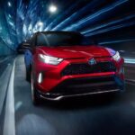 The newest Toyota RAV4 Prime for sale, a red 2023 Toyota RAV4 Prime, is shown driving through a tunnel.