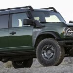 A green 2024 Ford Bronco Everglades is shown parked off-road after viewing a Ford Bronco for sale.