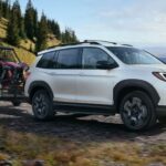 One of many popular Honda SUVs for sale, a white 2023 Honda Passport, is shown towing a trailer.