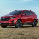 A red 2024 Chevy Equinox RS is shown parked near a lake after a 2024 Chevy Equinox vs 2024 Nissan Rogue comparison.