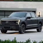 A gray 2024 Ford F-150 Lightning is shown parked on a driveway near a Ford F-150 Lightning dealer.