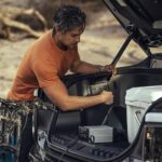 A person is shown plugging a plug into an outlet on a 2023 Ford F-150 Lightning.