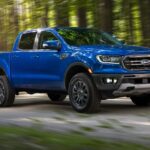 One of many popular used Ford trucks for sale, a blue 2019 Ford Ranger, is shown driving off-road.