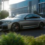 A grey 2023 BMW 5 Series sedan driving through the city to a BMW dealer.