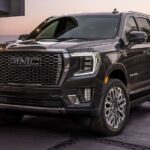 A black 2024 GMC Yukon Denali parked outside a home at dusk.