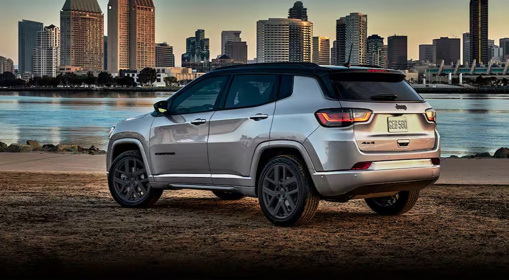 A silver 2024 Jeep Compass is shown parked near a city.