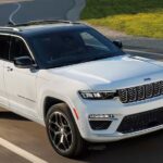 A white 2024 Jeep Grand Cherokee for sale driving on an open road.