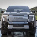 Front view of a grey 2024 GMC Sierra EV Denali Edition 1 parked on wet pavement.