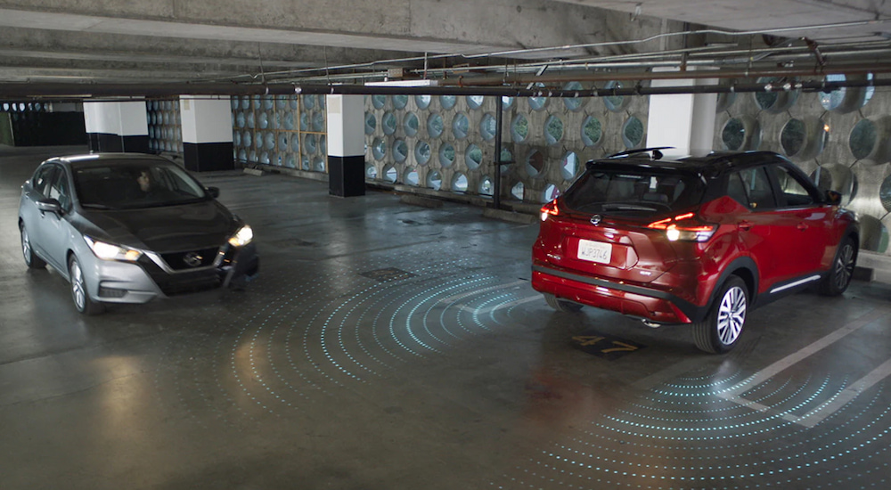 Simulated sensor lines showing the Nissan Safety Shield emanating from a red 2024 Nissan Kicks in a parking garage.