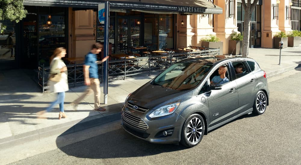 A grey 2017 Ford C-Max Energi is parked on the side of a city street.