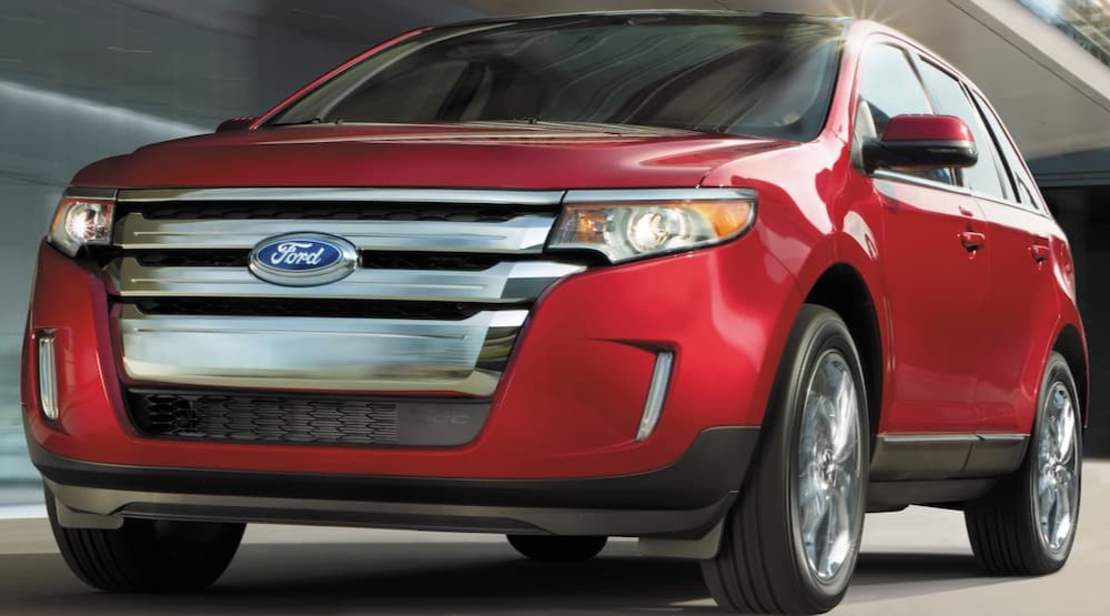 A red 2014 Ford Edge for sale is shown driving on a city street.