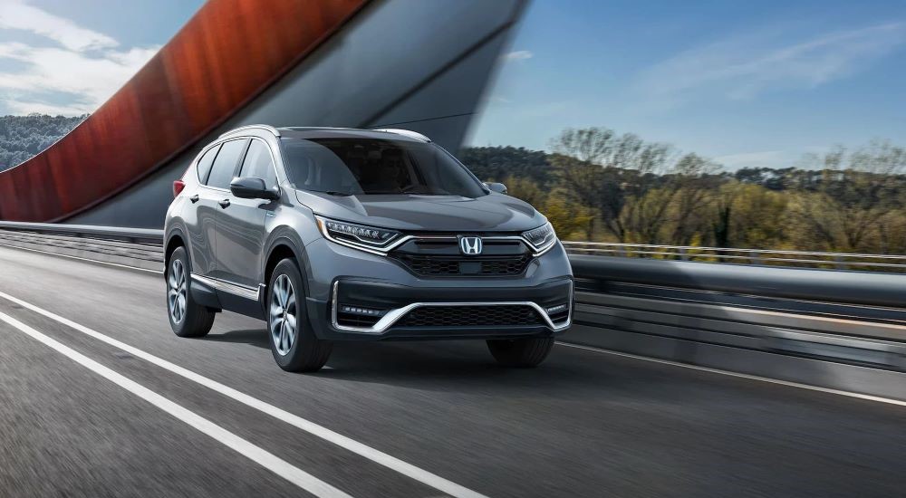 A gray 2020 Honda CR-V is shown driving on a bridge to view used cars for sale.