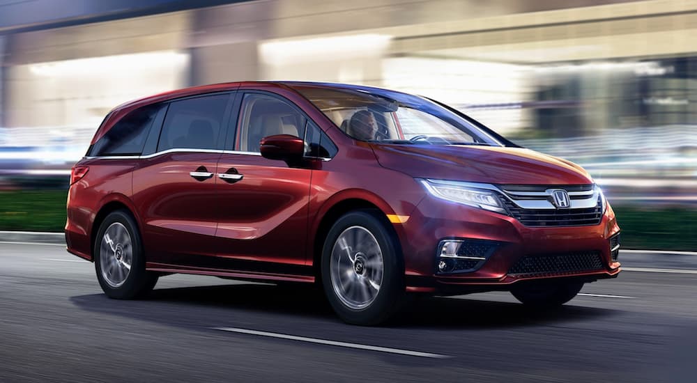 A red 2020 Honda Odyssey is shown driving on a city street.