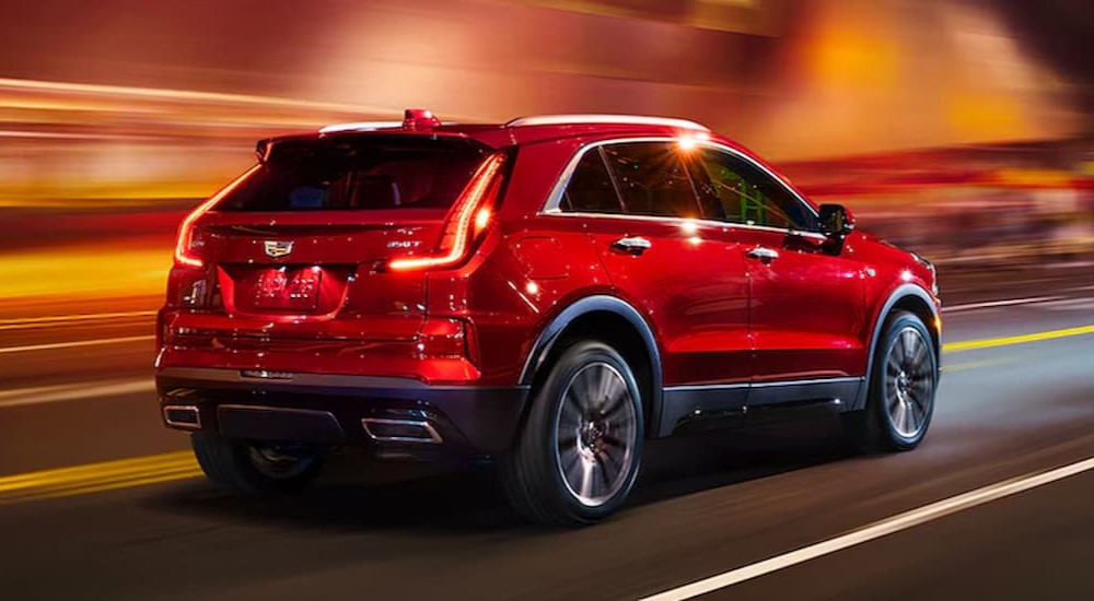 A red 2024 Cadillac XT4 for sale is shown driving on a highway.