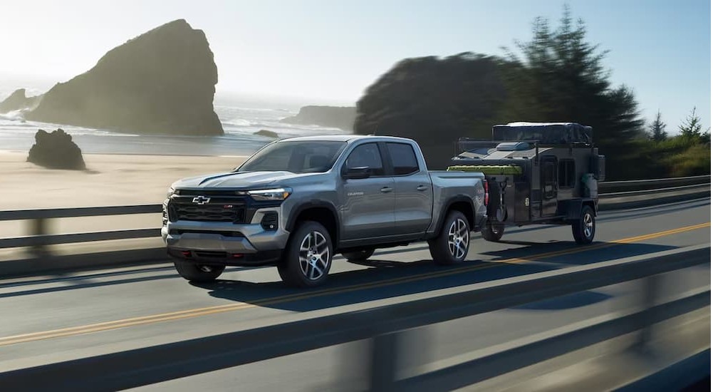 A silver 2024 Chevy Colorado Z71 is shown towing a trailer on a highway.