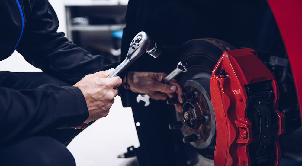 A mechanic is shown performing auto service on the brakes of a car.