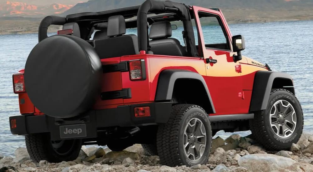 A red 2016 Jeep Wrangler Rubicon is shown parked near a lake.