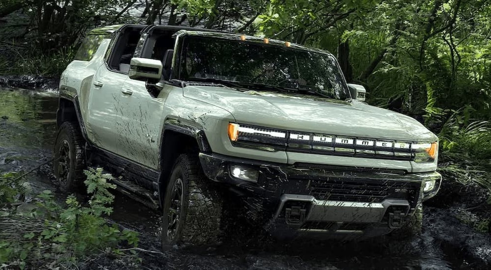 A green 2024 GMC Hummer EV is shown driving off-road.