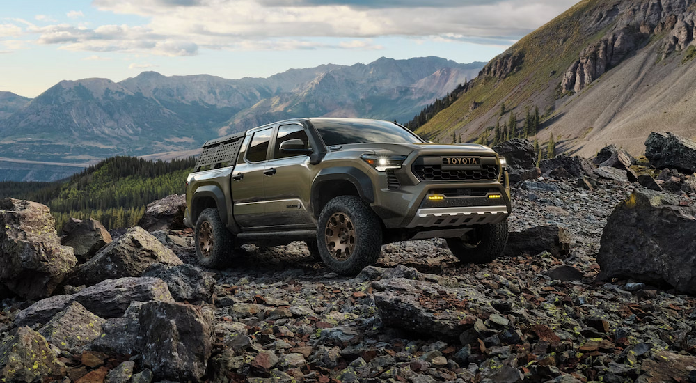 A green 2024 Toyota Tacoma Trailhunter Hybrid off-roading in the mountains.