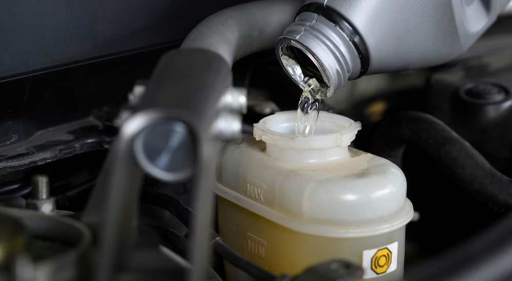 Brake fluid is shown being poured into a reservoir.