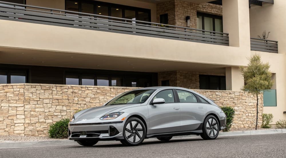 A silver 2024 Hyundai IONIQ 6 is shown parked near a building.