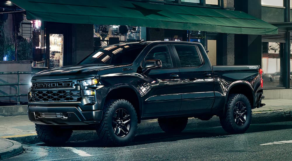 A black 2024 Chevy Silverado Z71 Trail Boss is shown from the side on a city street after leaving a Chevy dealer.