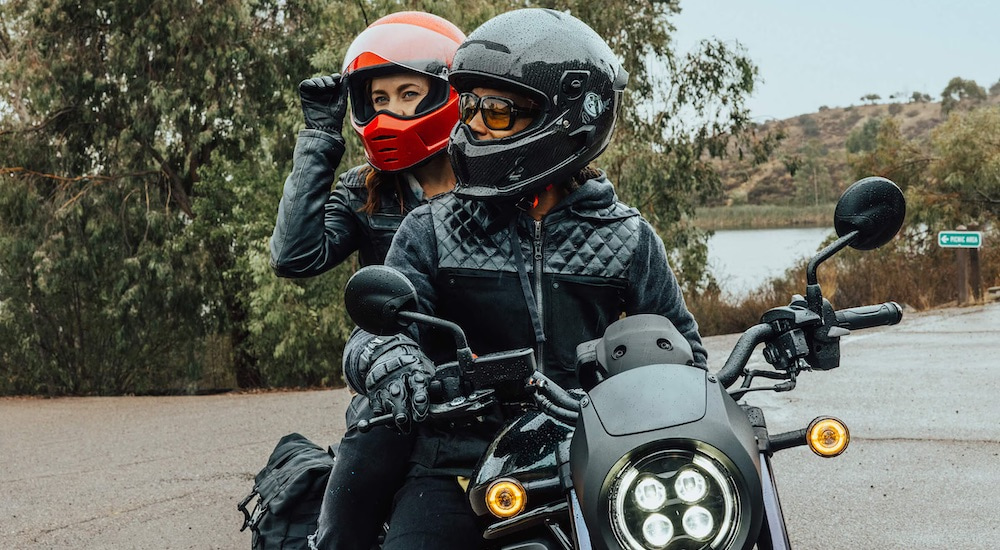 A close-up shows two people on a black 2023 Honda Rebel 1100 DCT after leaving a motorcycle dealer.