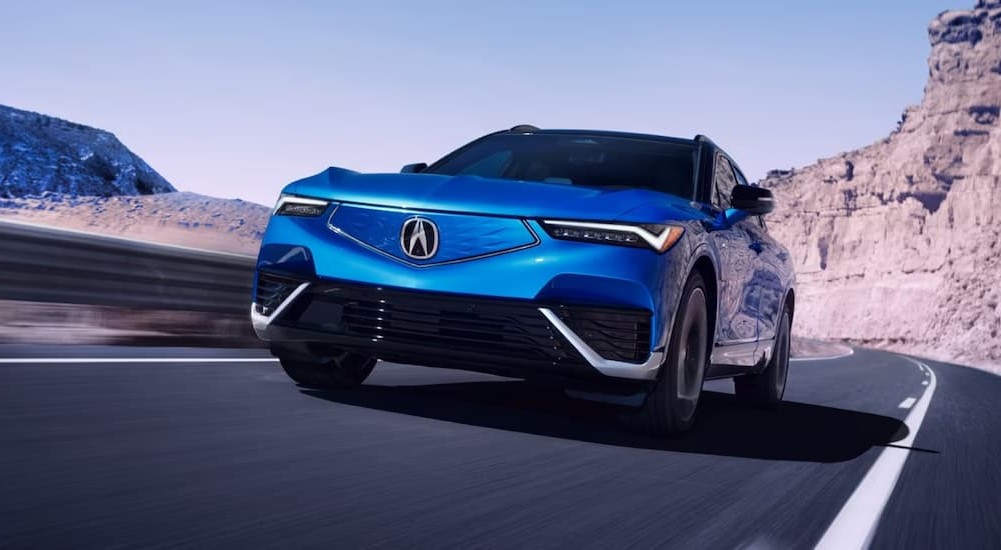 A blue 2024 Acura ZDX is shown driving on a highway.