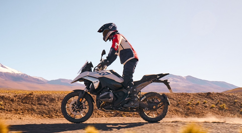 A white 2024 BMW R1300GS is shown from the side while off-road.