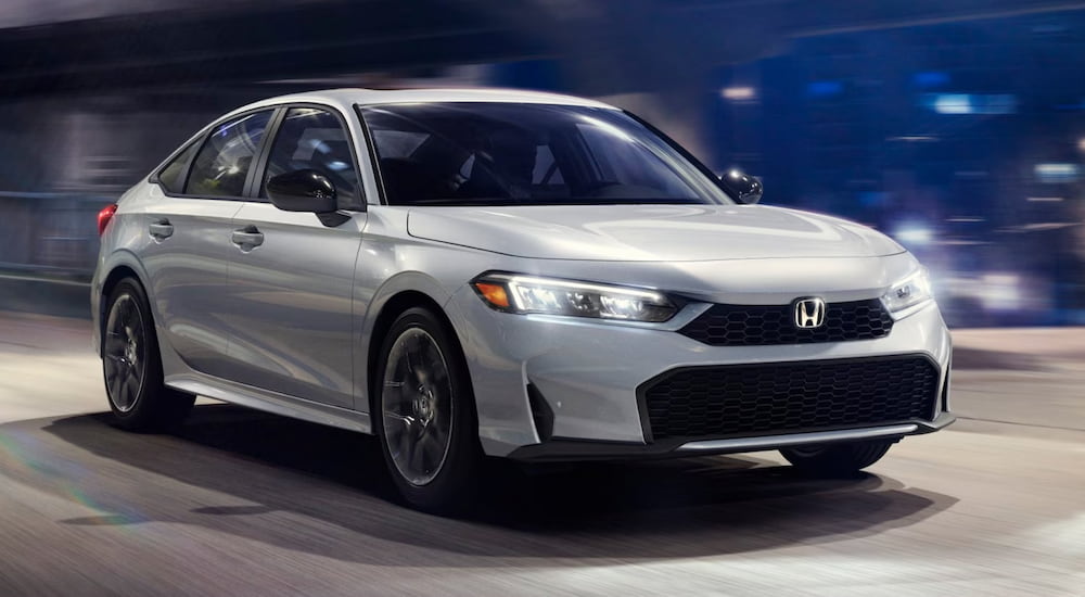 A white 2025 Honda Civic Hybrid driving and angled right.