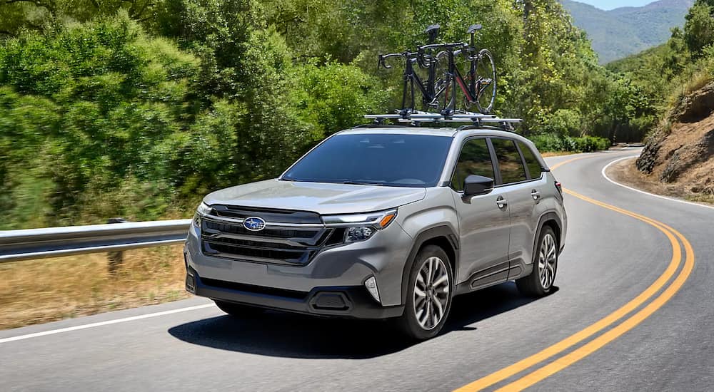 A grey 2025 Subaru Forest driving down a winding road.