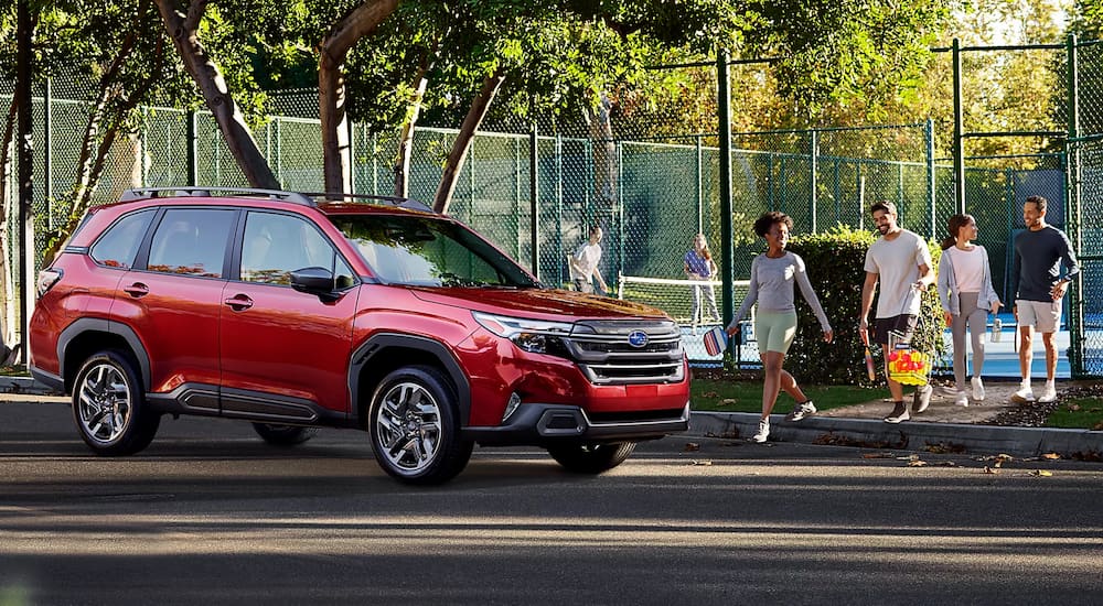 A red 2025 Subaru Forester parked by a park and angled right.