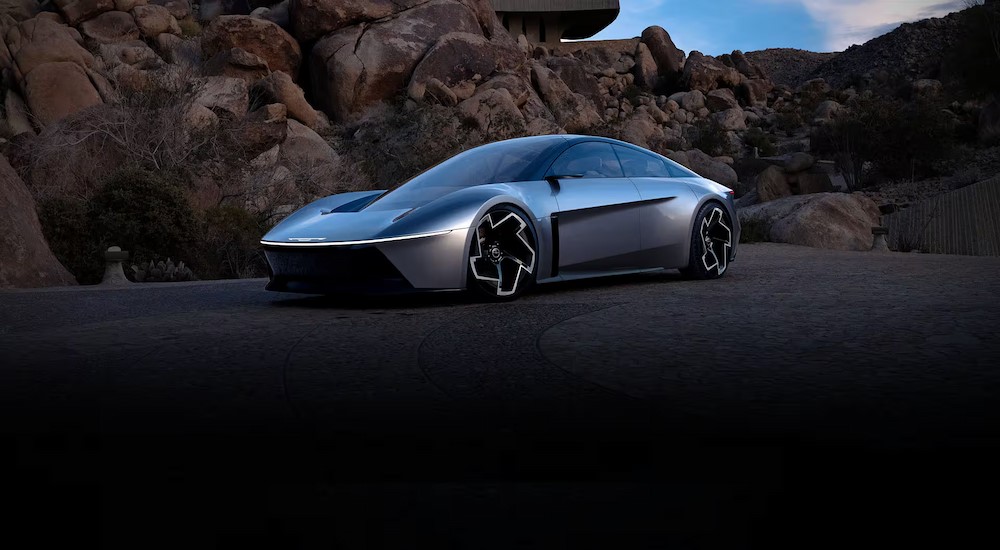 A silver Chrysler Halcyon concept car is shown parked near boulders.